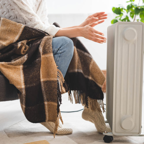 cropped view of girl with blanket warming up with heater in cold room - Best Portable Space Heaters of 2021